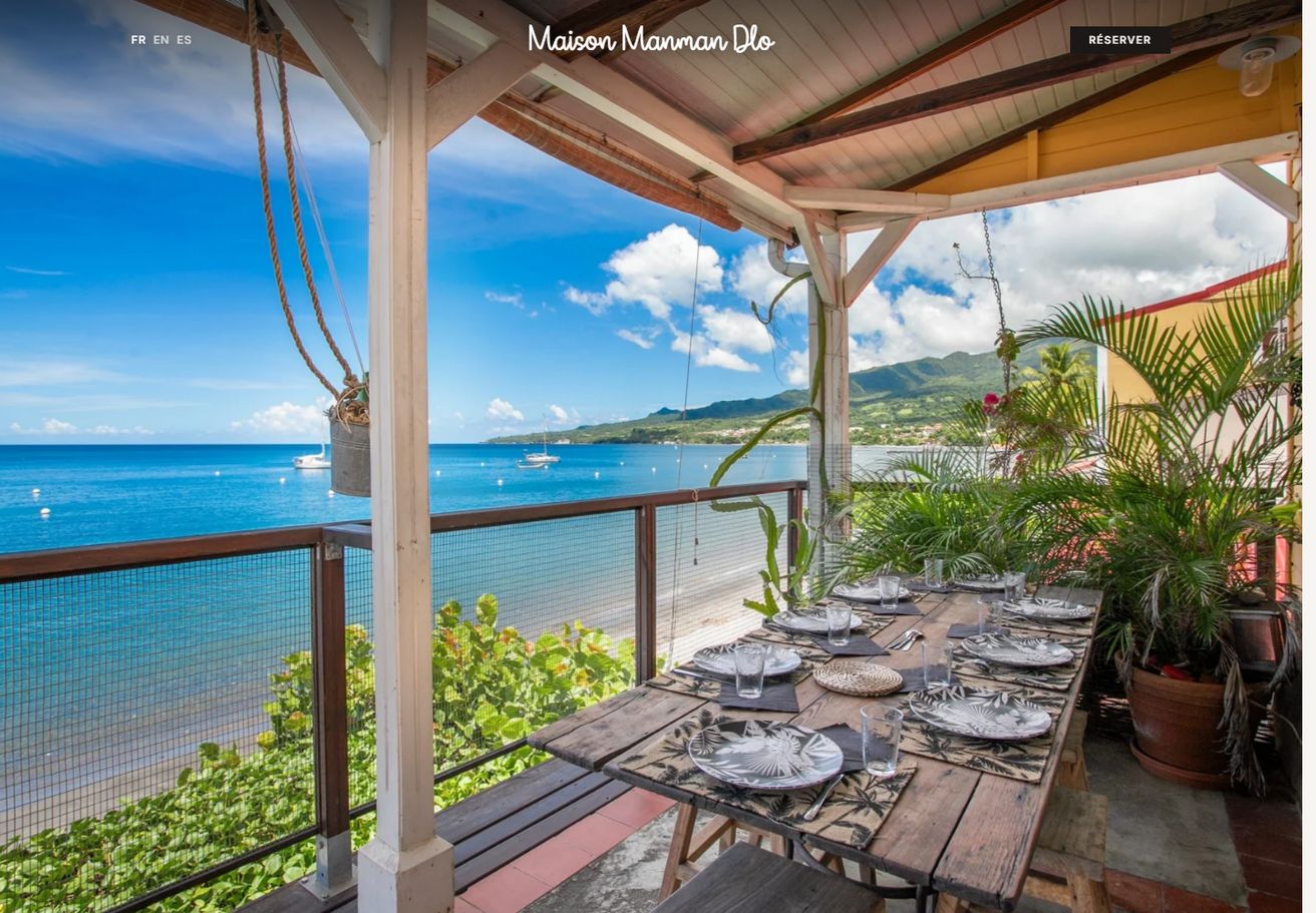 Page d’accueil du site de la Maison Manman Dlo, une terrasse en bord de mer face à la baie
