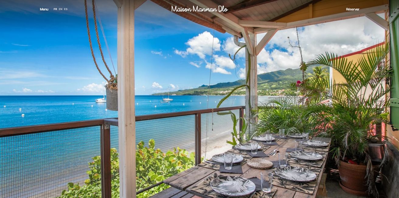 Page d’accueil du site de la Maison Manman Dlo, une terrasse en bord de mer face à la baie